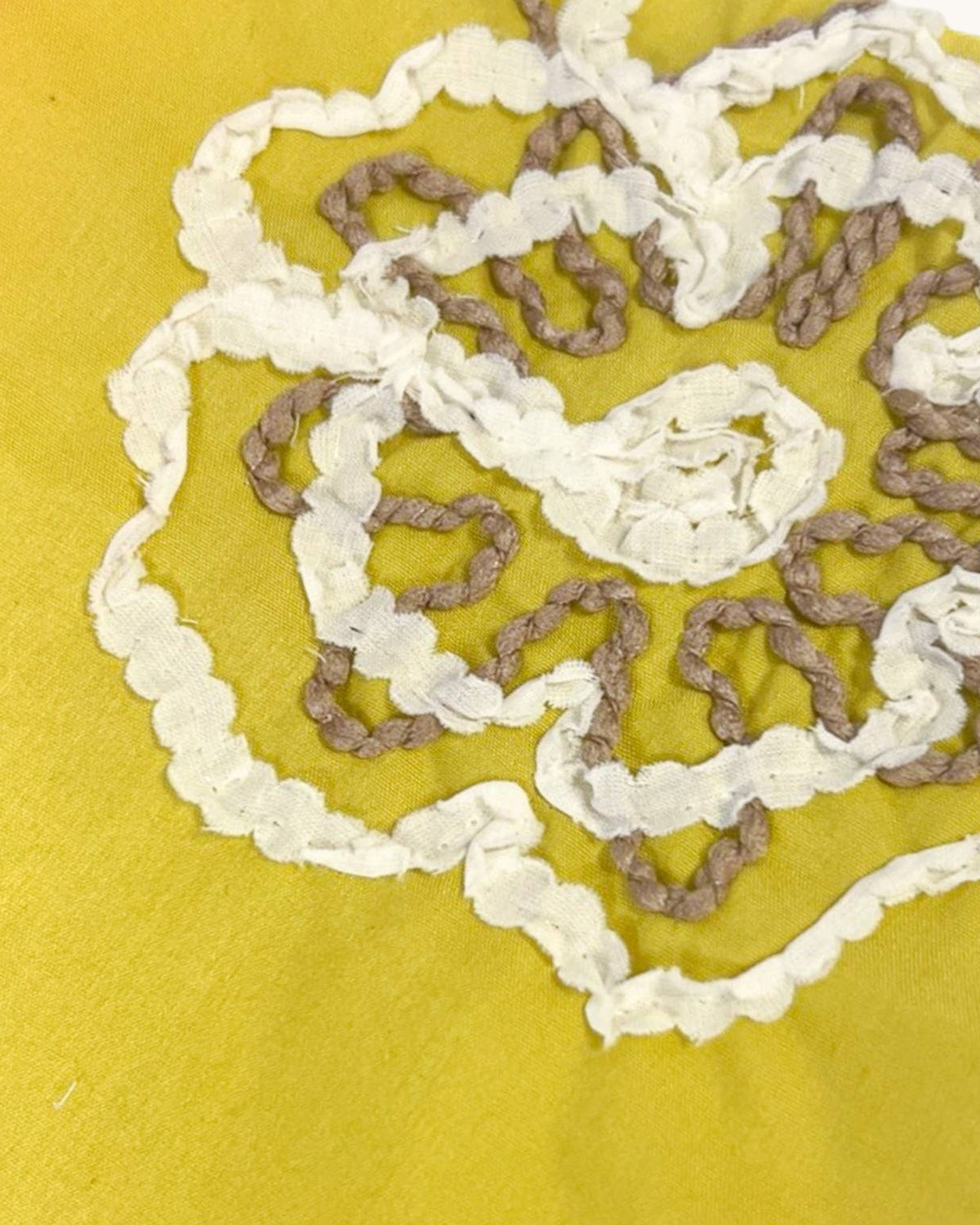 A close-up of a yellow-green (Olive) fabric featuring a hand-embroidered or lace applique design in white and taupe-brown.