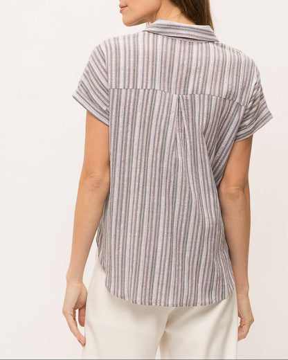 Woman wearing striped short sleeve button-up shirt with wrap front drape, collar and gold lurex detail.