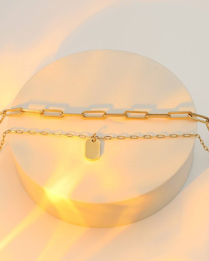 Gold chain necklace with a tag on a light background