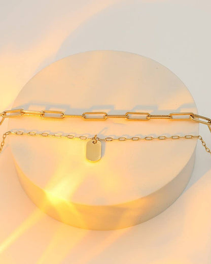Gold chain necklace with a tag on a light background