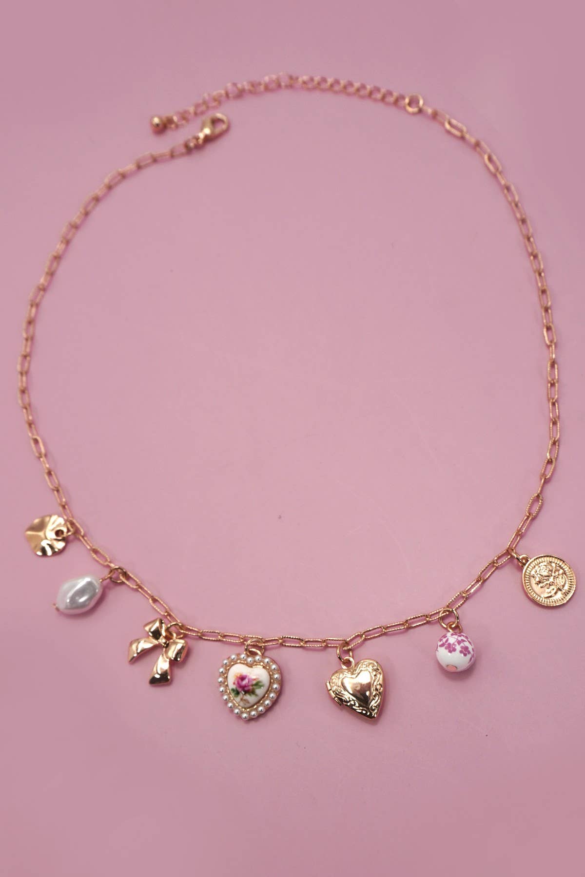 Necklace with various charms on a pink background.