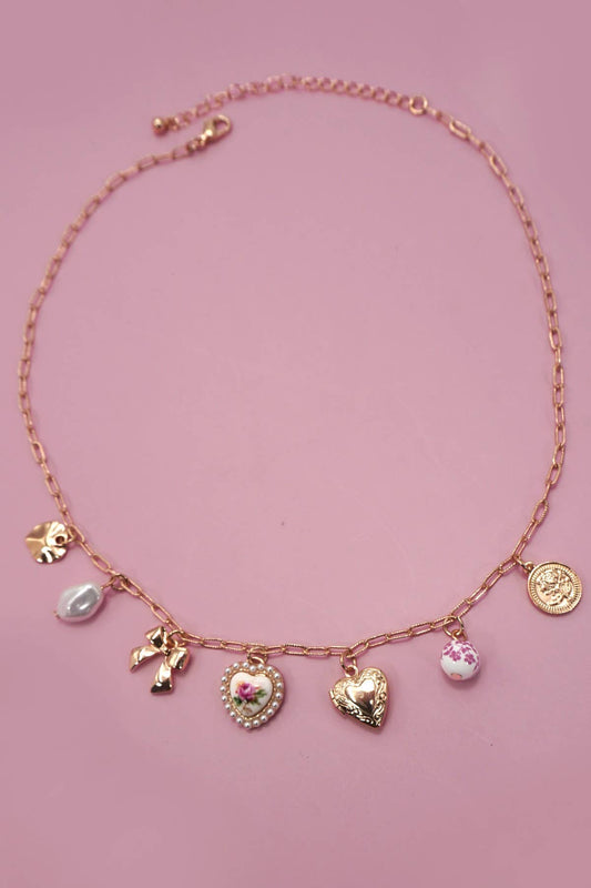 Necklace with various charms on a pink background.