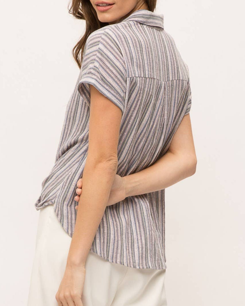 Woman wearing striped short sleeve button-up shirt with wrap front drape, collar and gold lurex detail.