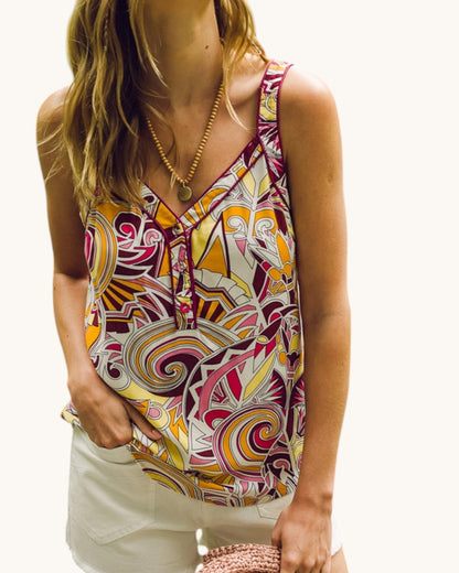 Woman wearing a colorful patterned sleeveless top on a white background.