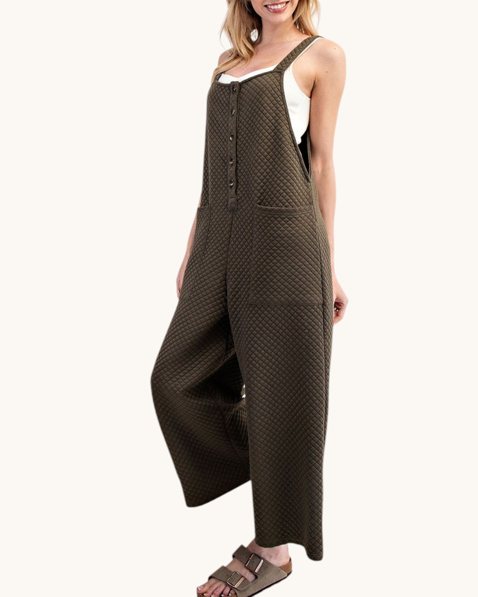 Woman wearing a moss colored sleeveless textured jumpsuit on a white background.
