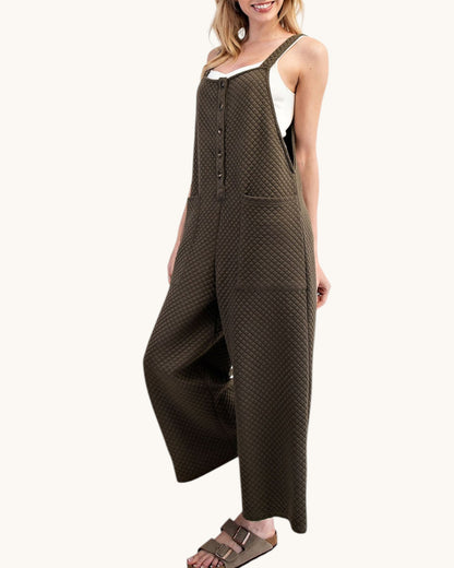 Woman wearing a moss colored sleeveless textured jumpsuit on a white background.