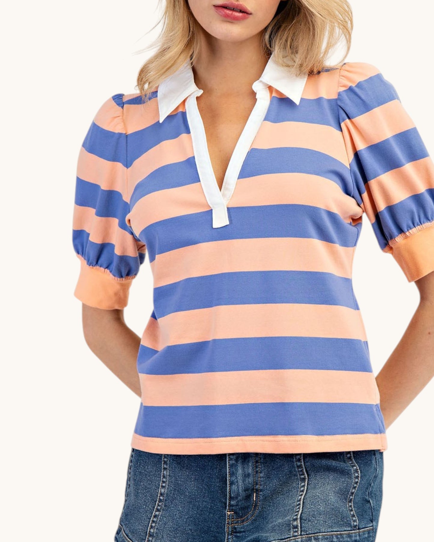 Woman wearing a blue and peach striped shirt with a white collar on a plain background.