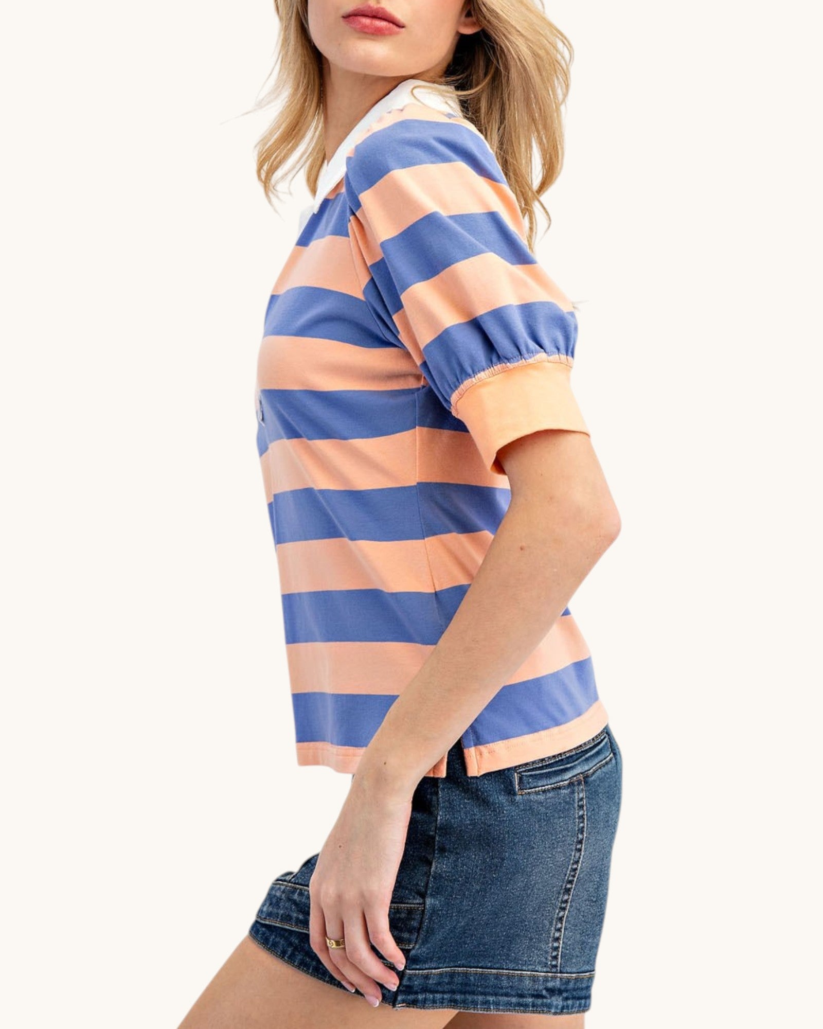 Woman wearing a striped shirt and denim shorts on a white background.