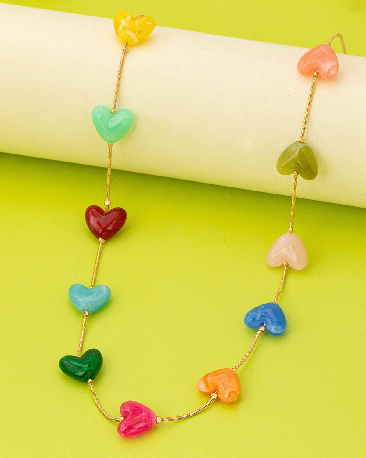 Necklace with colorful heart-shaped beads on a green background.