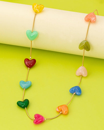 Necklace with colorful heart-shaped beads on a green background.
