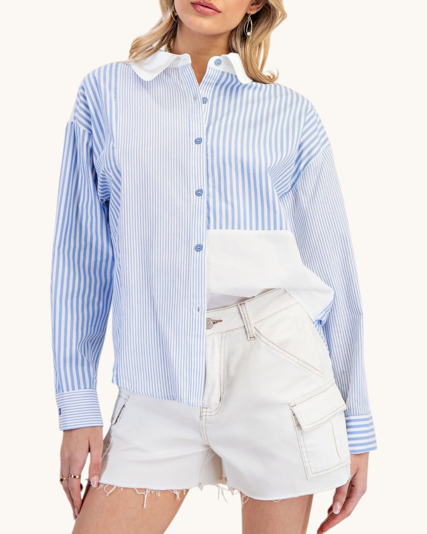 Woman wearing a blue and white striped shirt with a white collar and white shorts on a white background.