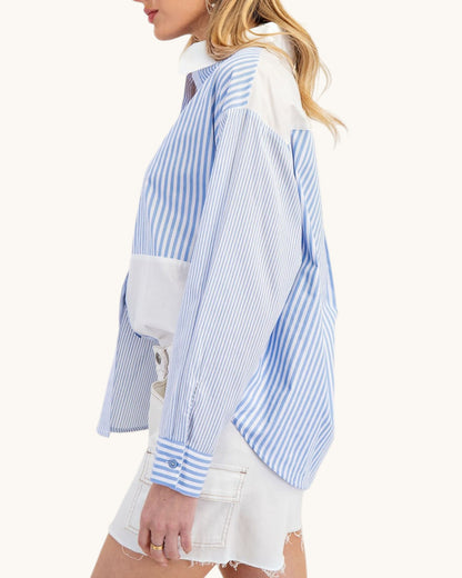 Woman wearing a blue and white striped shirt with a white background.