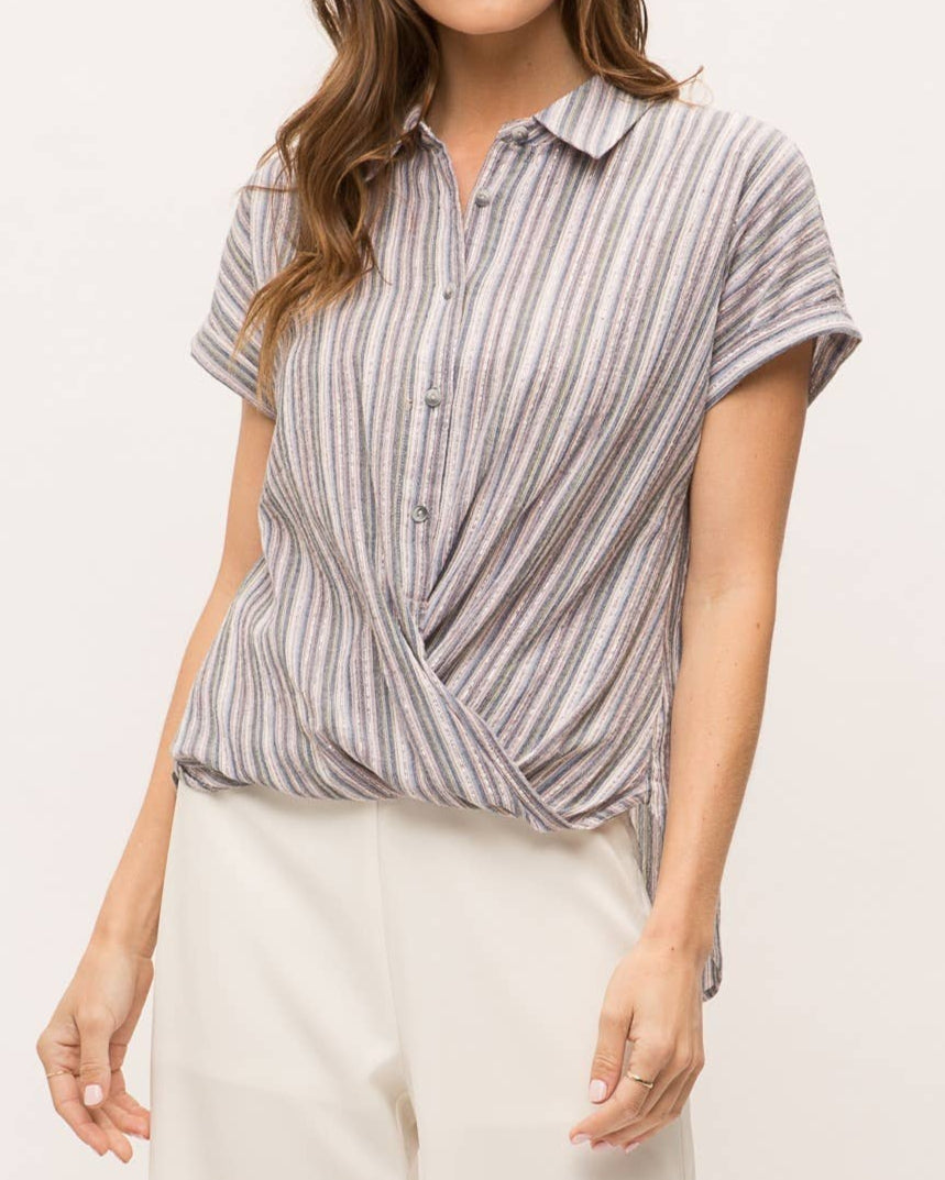 Woman wearing striped short sleeve button-up shirt with wrap front drape, collar and gold lurex detail.