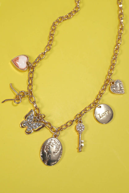 Gold charm statement necklace with a bow, heart, key, butterfly, and sparkling rhinestone accents.