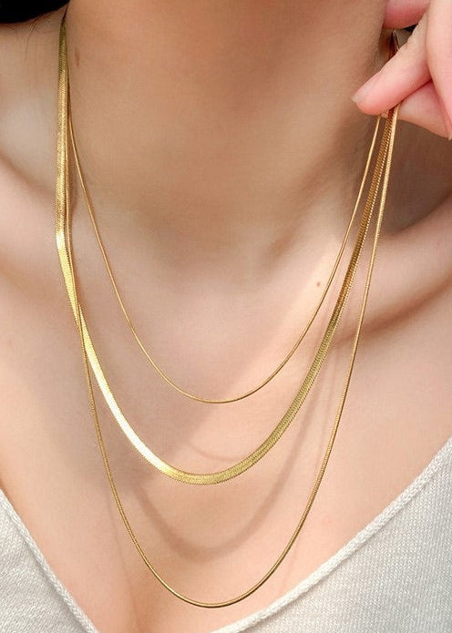 3-Layer Gold Herringbone necklace on a person's neck with a neutral background