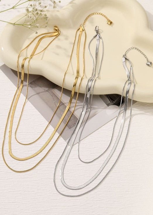Gold and silver necklaces on a white surface with a soft focus background