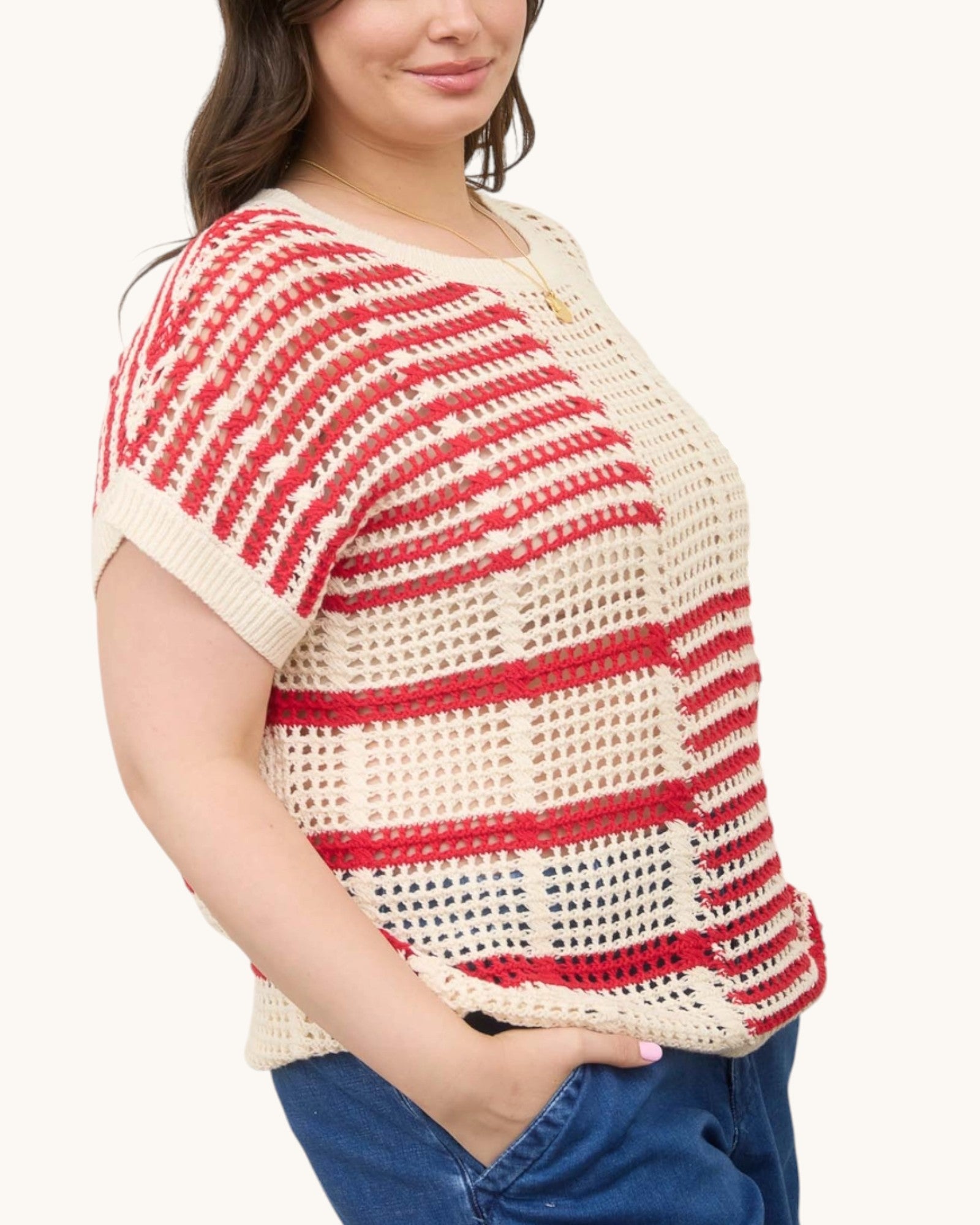 Woman wearing a red and white striped open knit crochet top on a white background, side view.