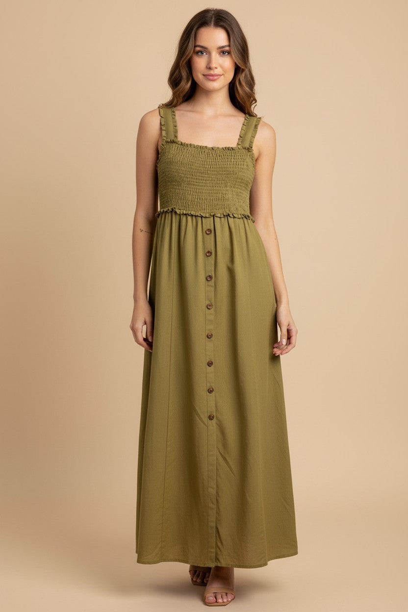 A woman modeling a sleeveless olive green maxi dress with a smocked bodice, square neckline, and a button-down front, set against a solid beige studio background.