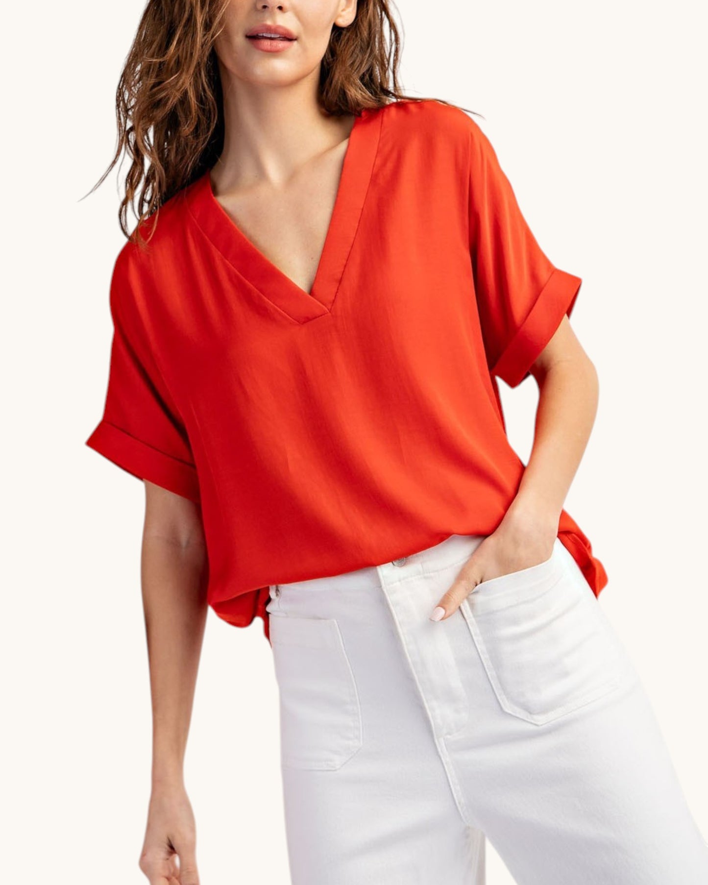 Tomato red V-neck top worn with white pants on white background, front view. 