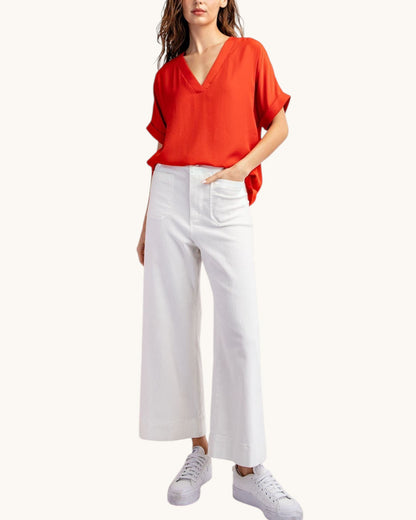 Front view, red v-neck short sleeve top and white ankle pants and white sneakers. 