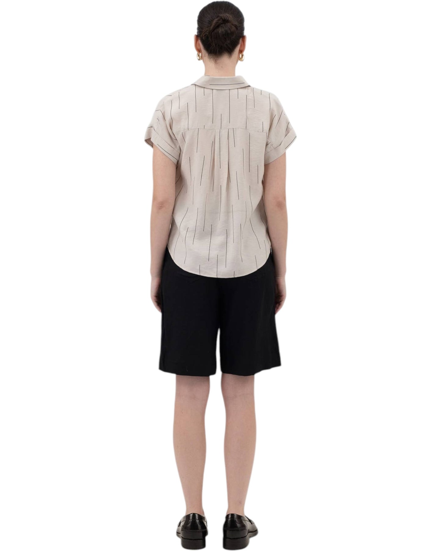 Person wearing a beige short-sleeve shirt and black shorts on a white background.