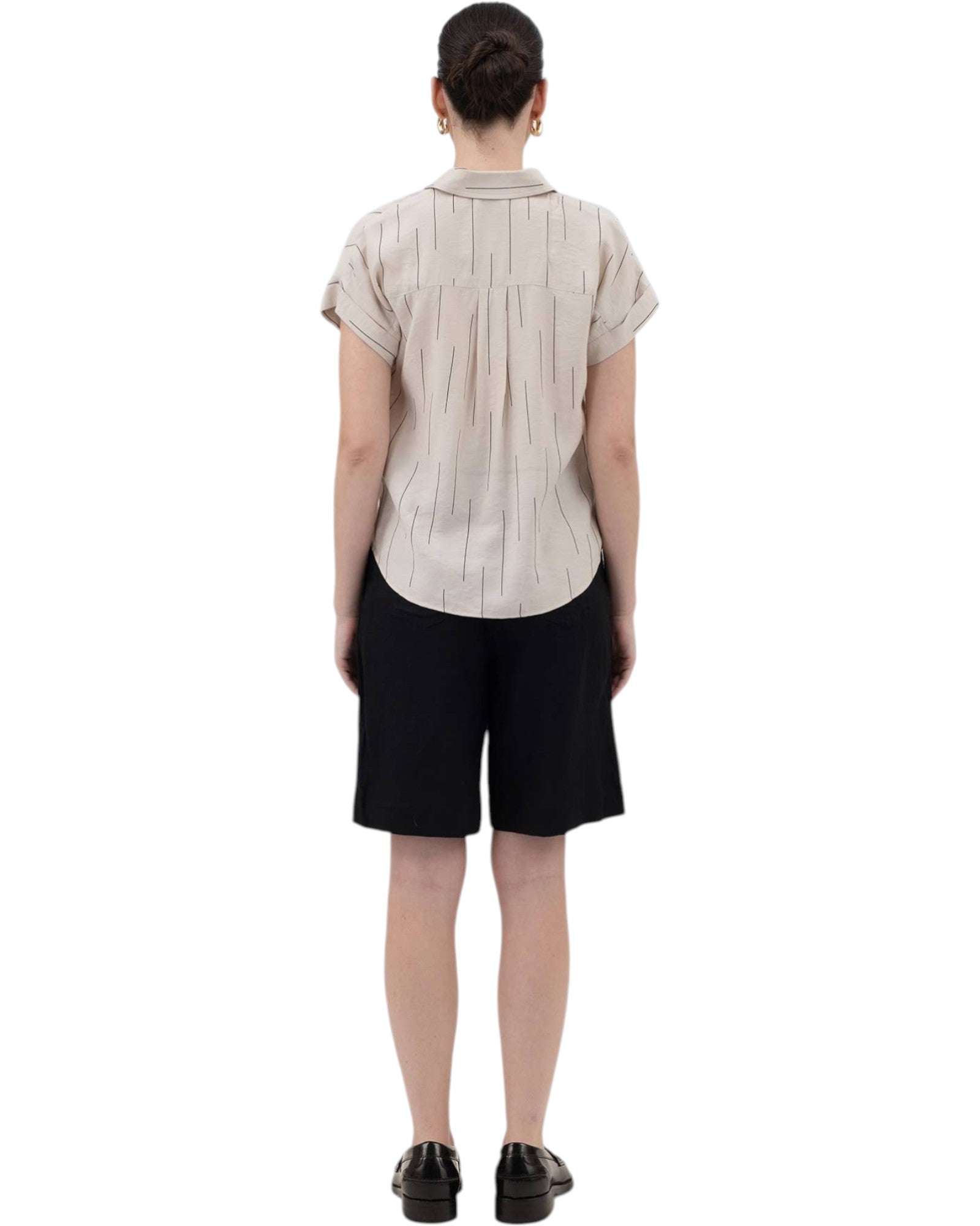 Person wearing a beige short-sleeve shirt and black shorts on a white background.