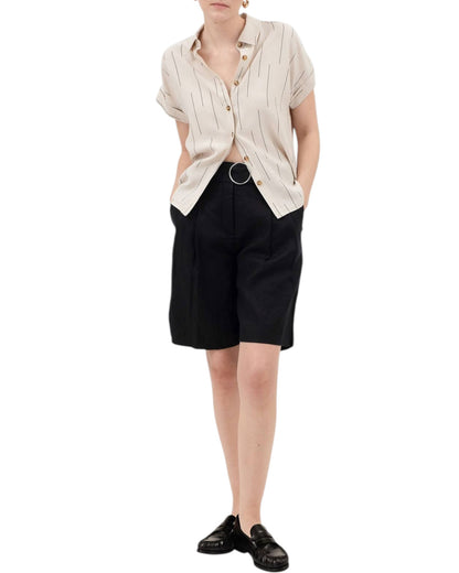 Person wearing a beige button-up shirt and black shorts on a white background.