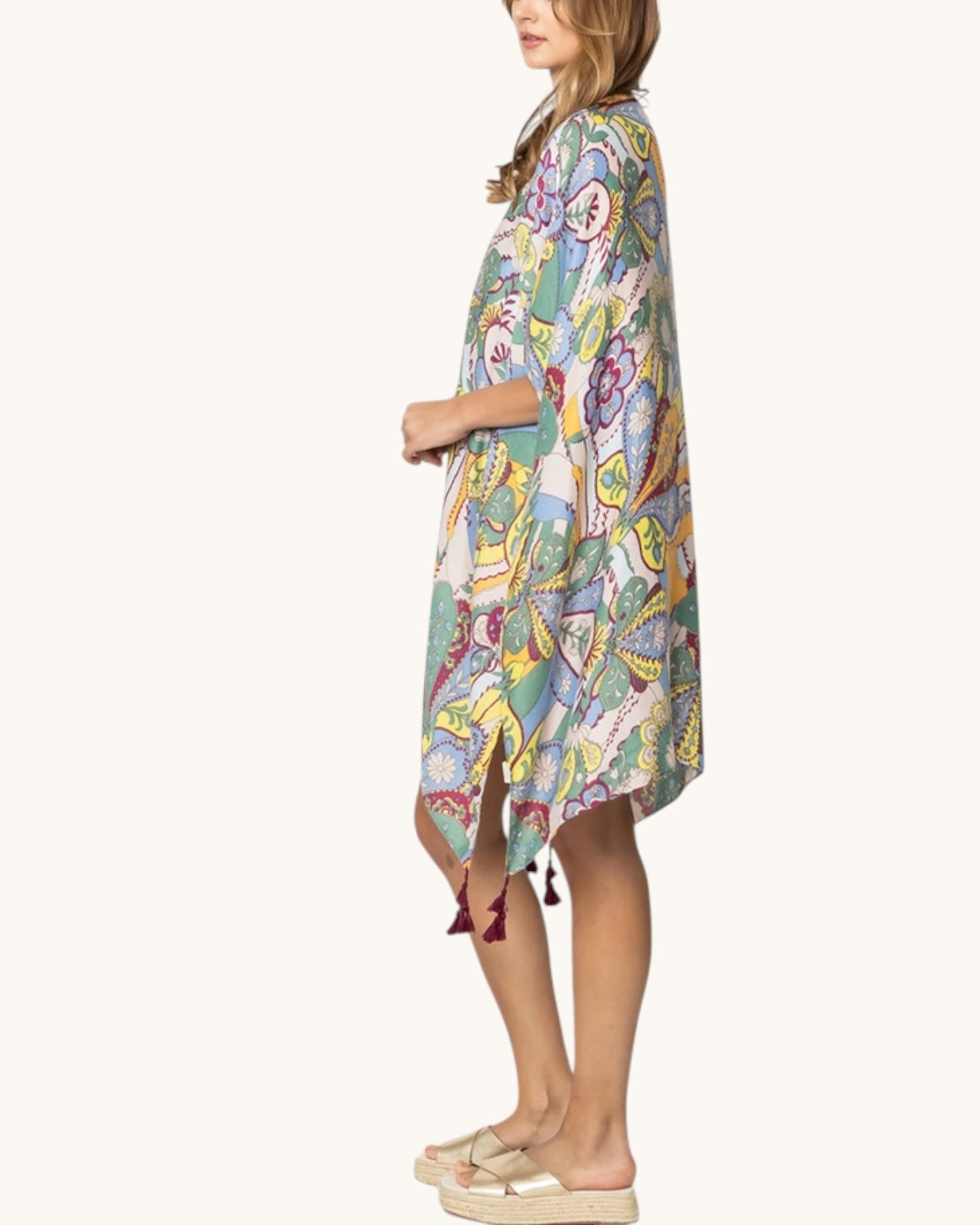 Woman wearing a colorful patterned cover up on a white background.