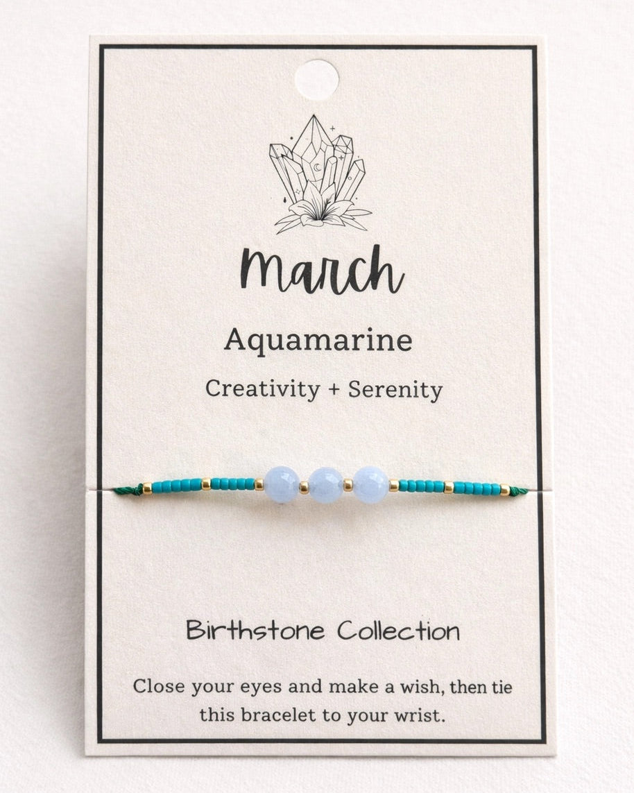 Bracelet with beads on a card labeled 'March Aquamarine' on a white background.