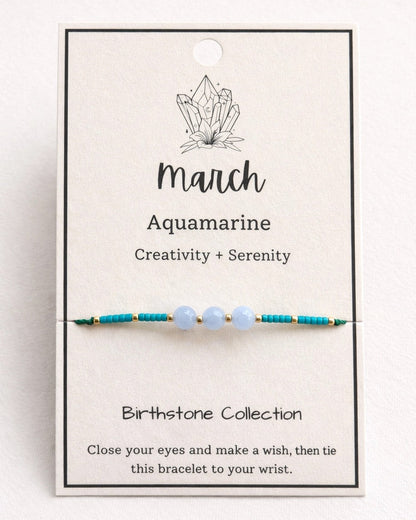 Bracelet with beads on a card labeled 'March Aquamarine' on a white background.