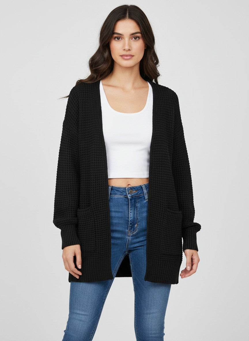 Woman wearing a black mid-thigh open front waffle knit cardigan with blue jeans and a white tank top. 