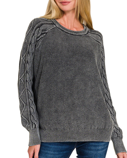 Woman wearing a charcoal cable knit sweater on a white background.