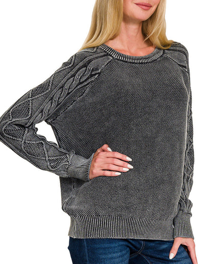 Woman wearing a charcoal sweater with cable knit design on a white background.