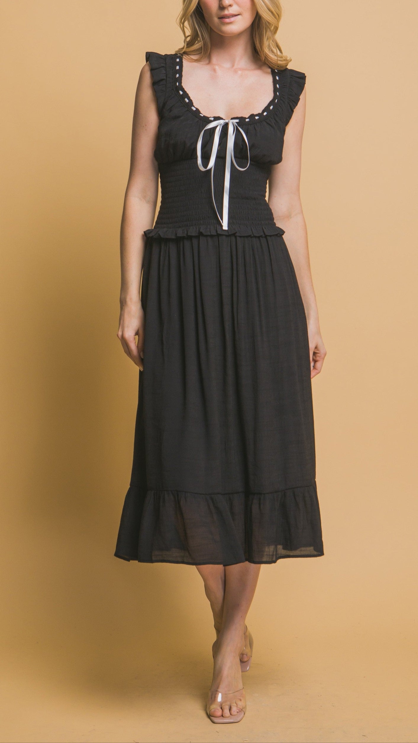 Black midi dress with white ribbon trim, smocked bodice, ruffle sleeves, and tiered hemline. Romantic and feminine style. 