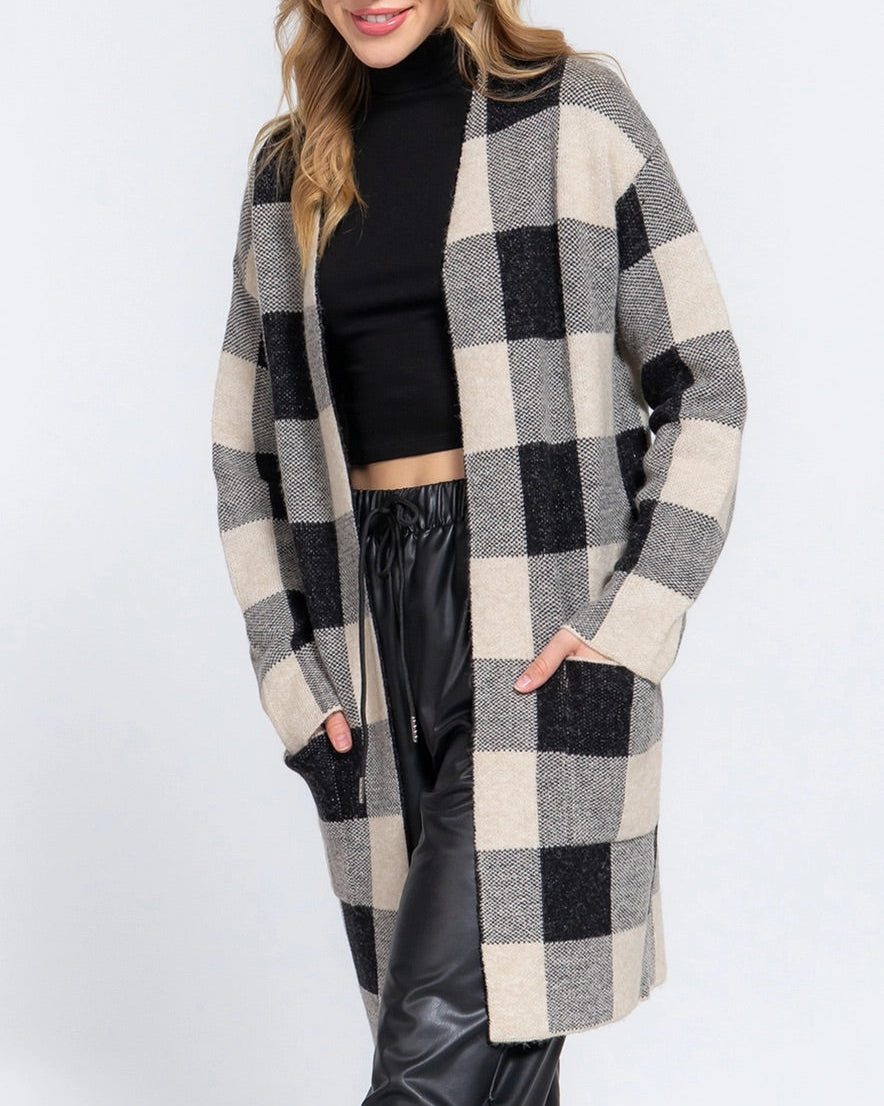 Woman wearing a black and cream checkered long cardigan on a white background.