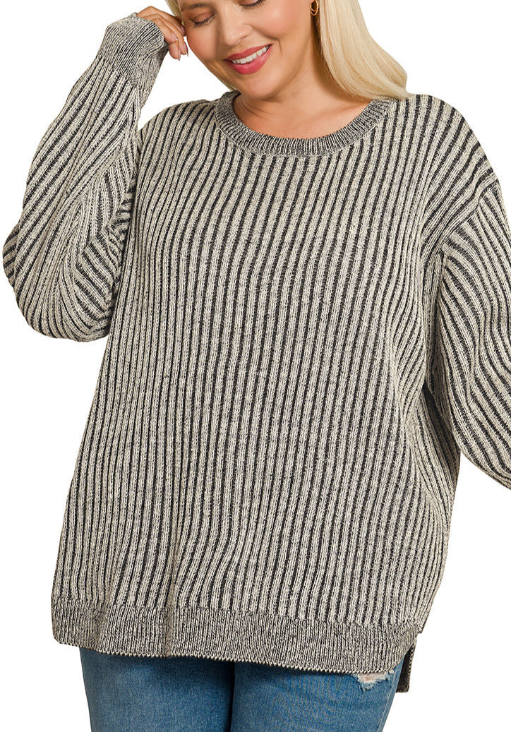 Woman wearing a black and gray striped sweater with blue jeans on a white background.