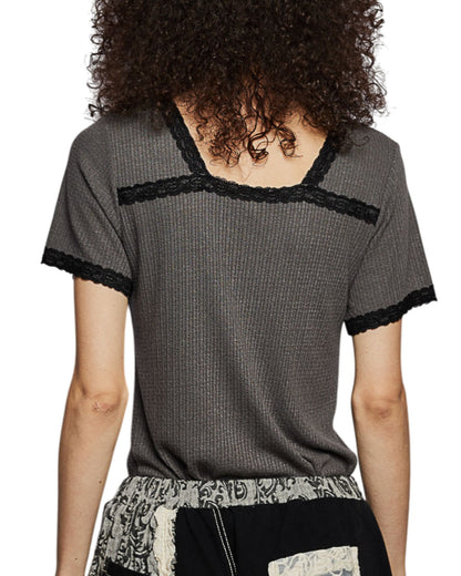 Person wearing a gray short-sleeve top with black trim on a white background