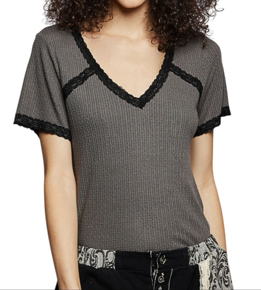 Woman wearing a gray ribbed top with black lace trim on a white background.