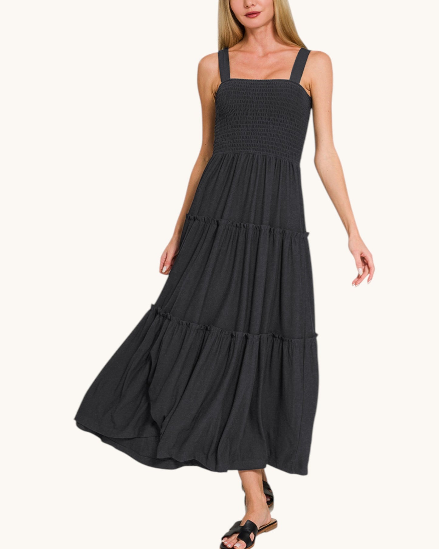 Woman wearing a black tiered dress on a white background.