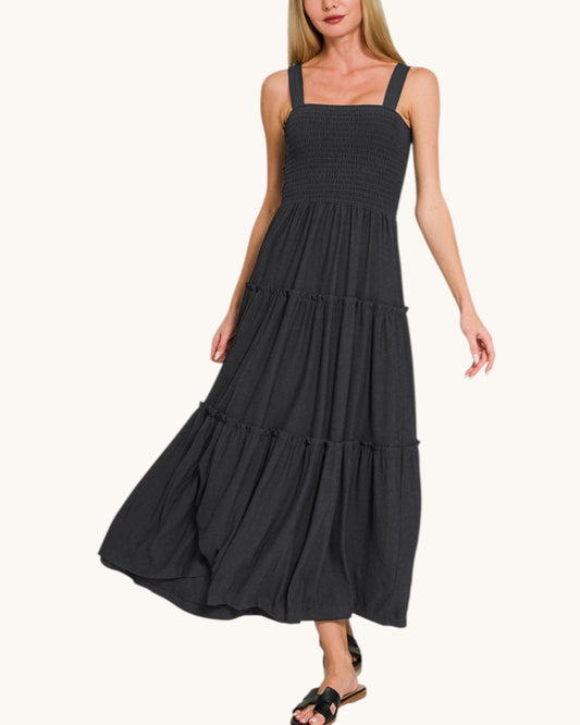 Woman wearing a black tiered dress on a white background.