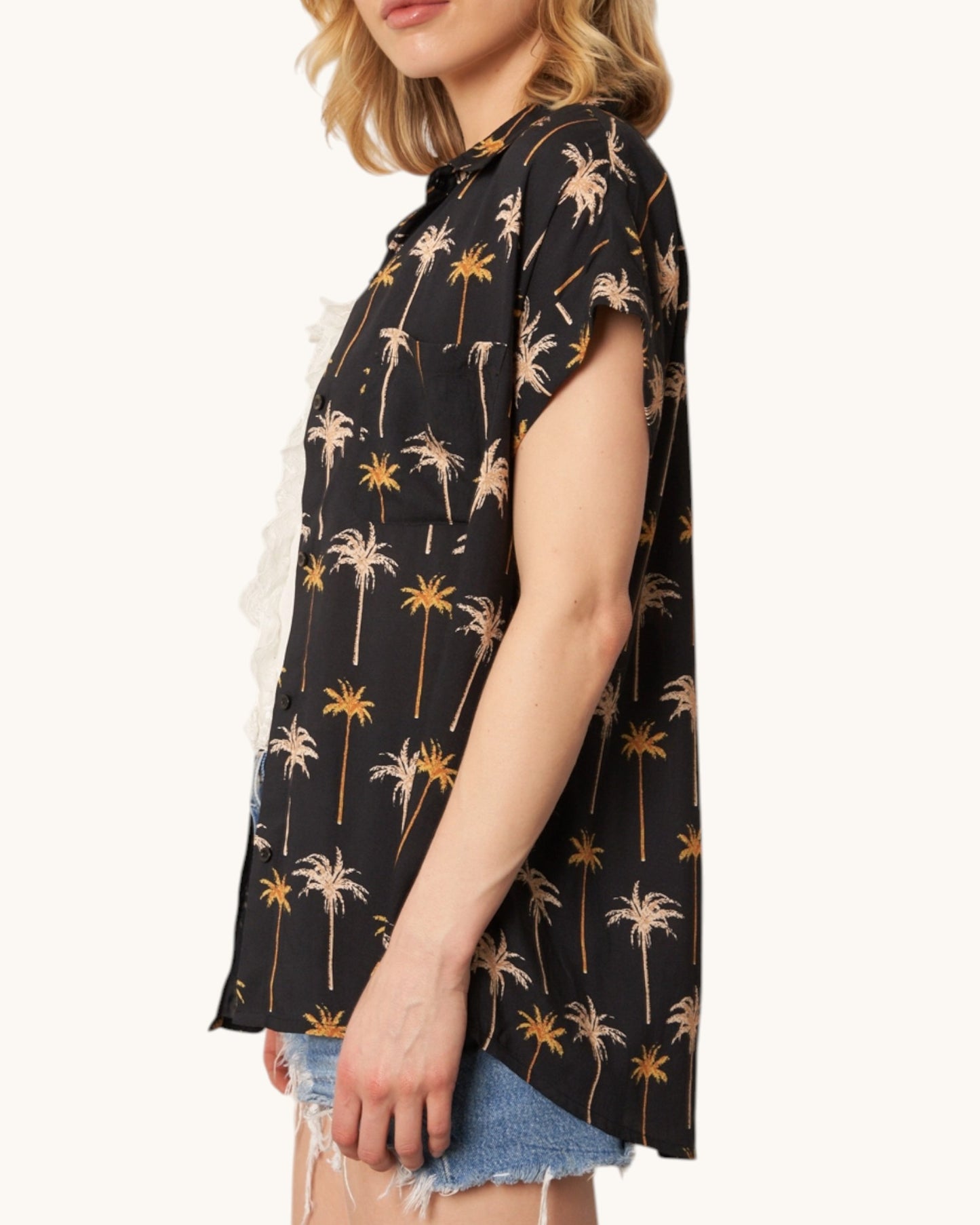 Side view of a black shirt with palm tree pattern worn by a person on a white background.