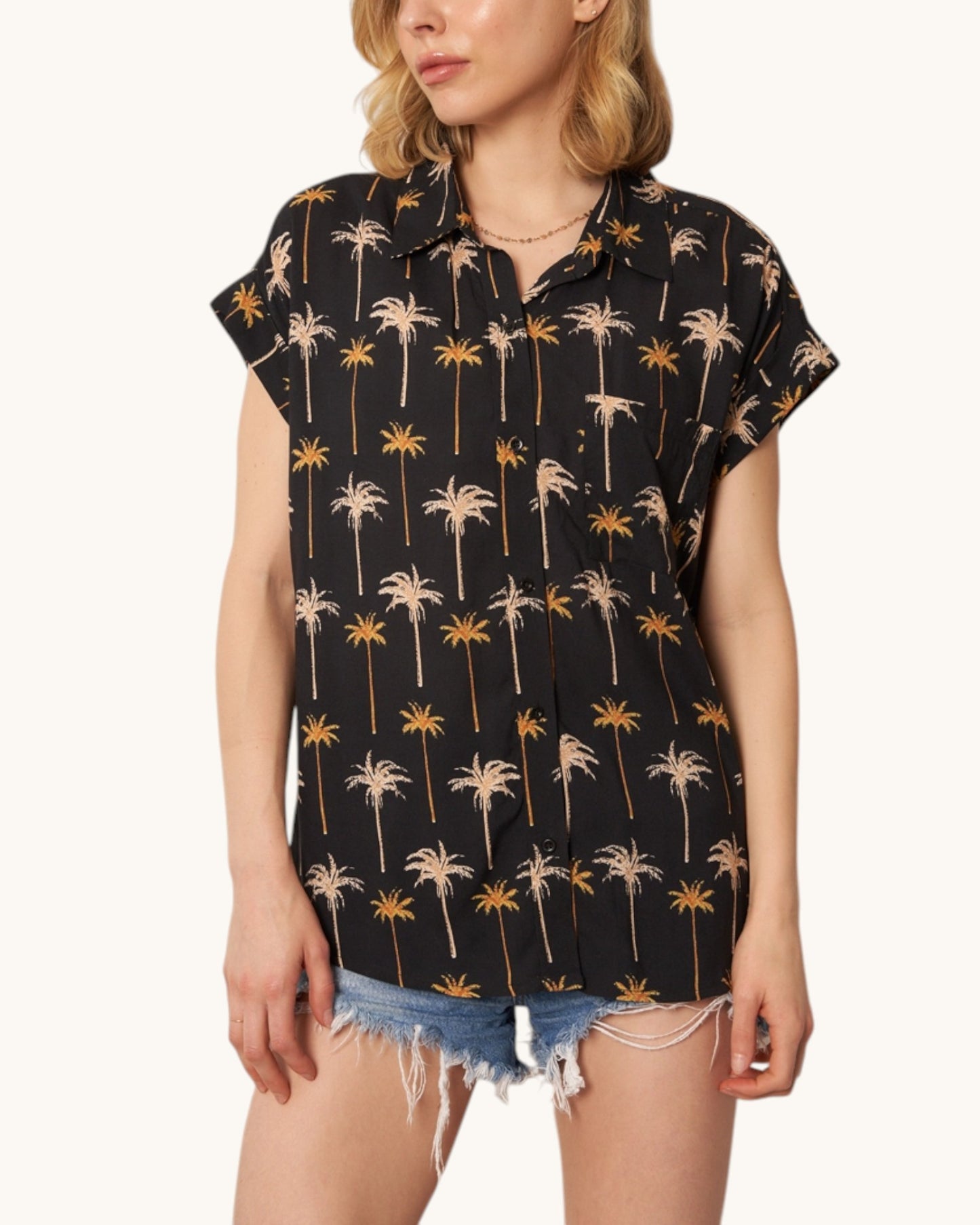 Woman wearing a black shirt with palm tree pattern on a white background.