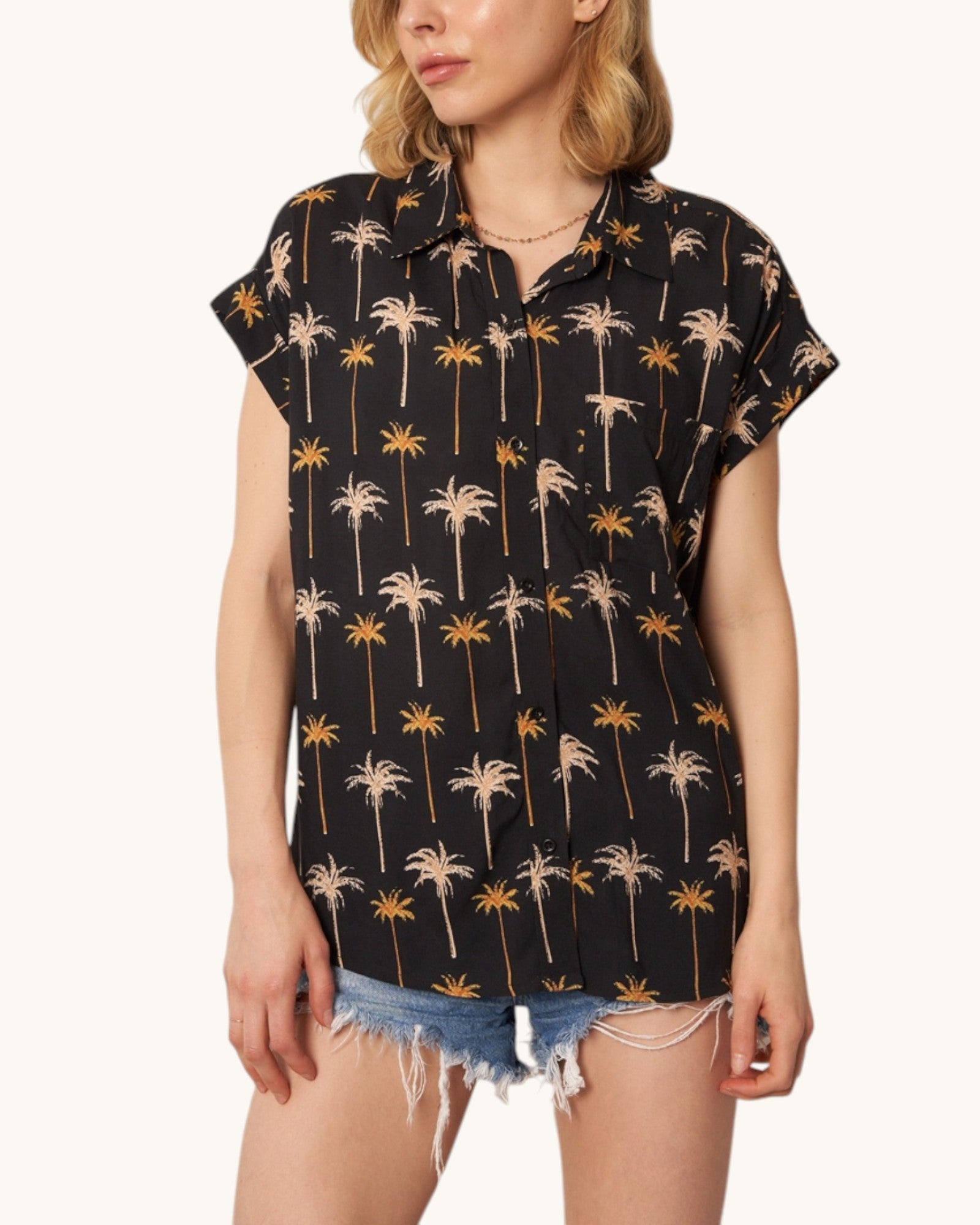 Woman wearing a black shirt with palm tree pattern on a white background.