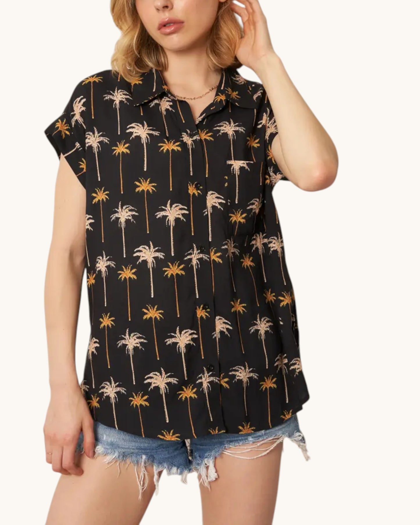 Woman wearing a black sleeveless shirt with palm tree pattern on a white background.