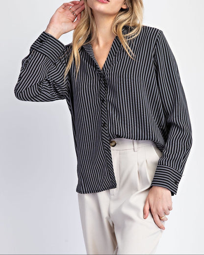 Woman wearing a black and white striped shirt with white pants on a light gray background.