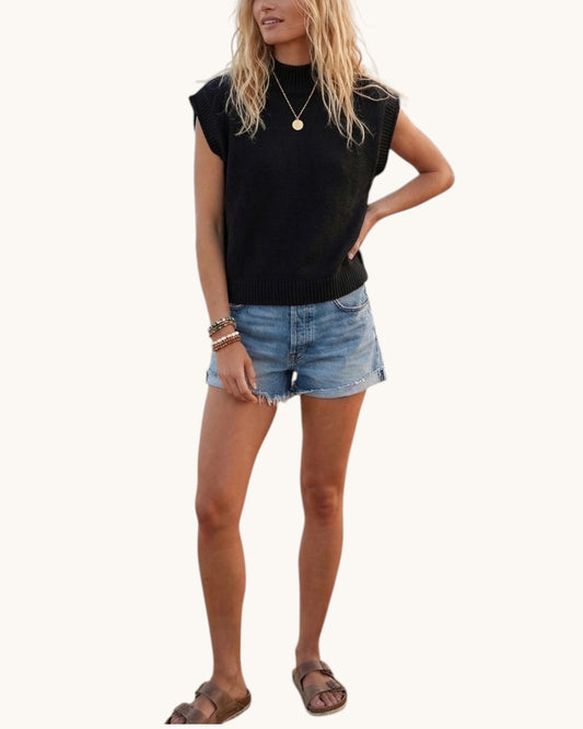 Woman wearing a black sleeveless top and denim shorts on a white background.