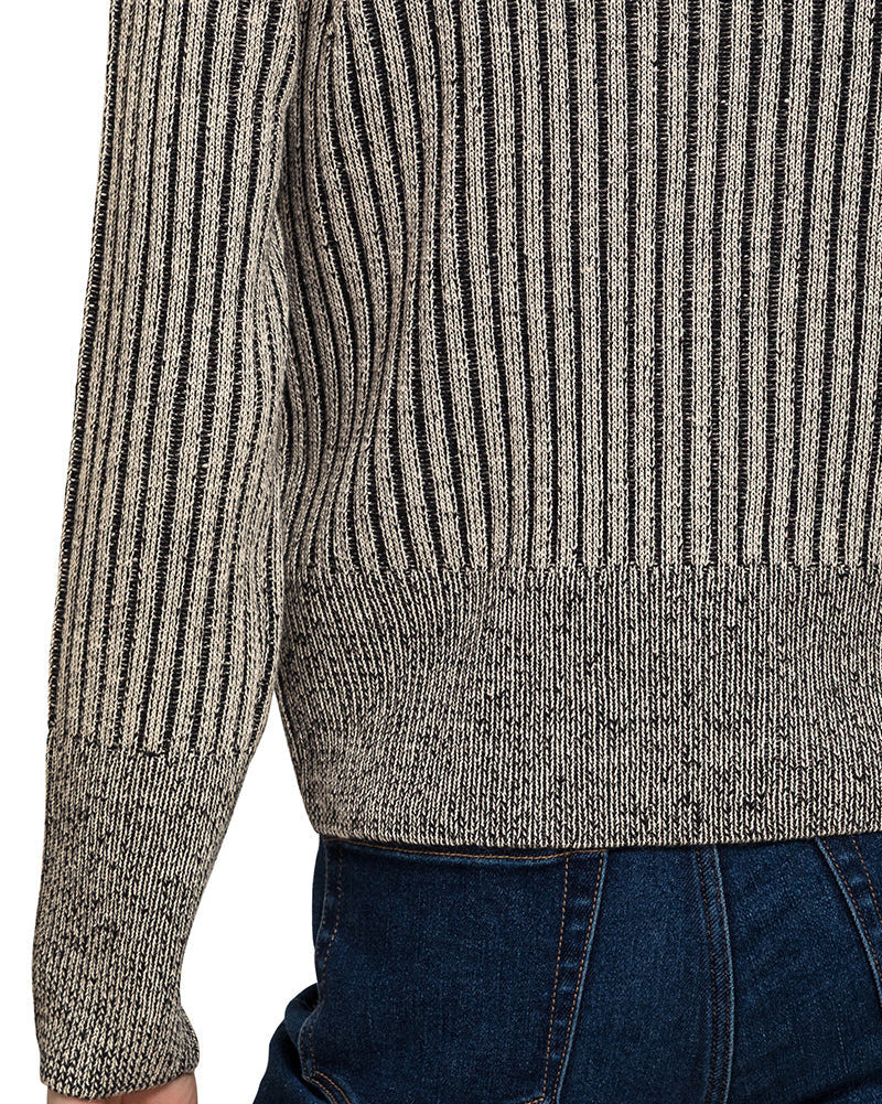 Woman wearing a charcoal ribbed knit zip up cardigan over a white top and blue jeans on a white background. 