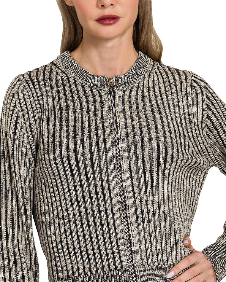Woman wearing a ribbed knit zip up cardigan sweater against a white background.