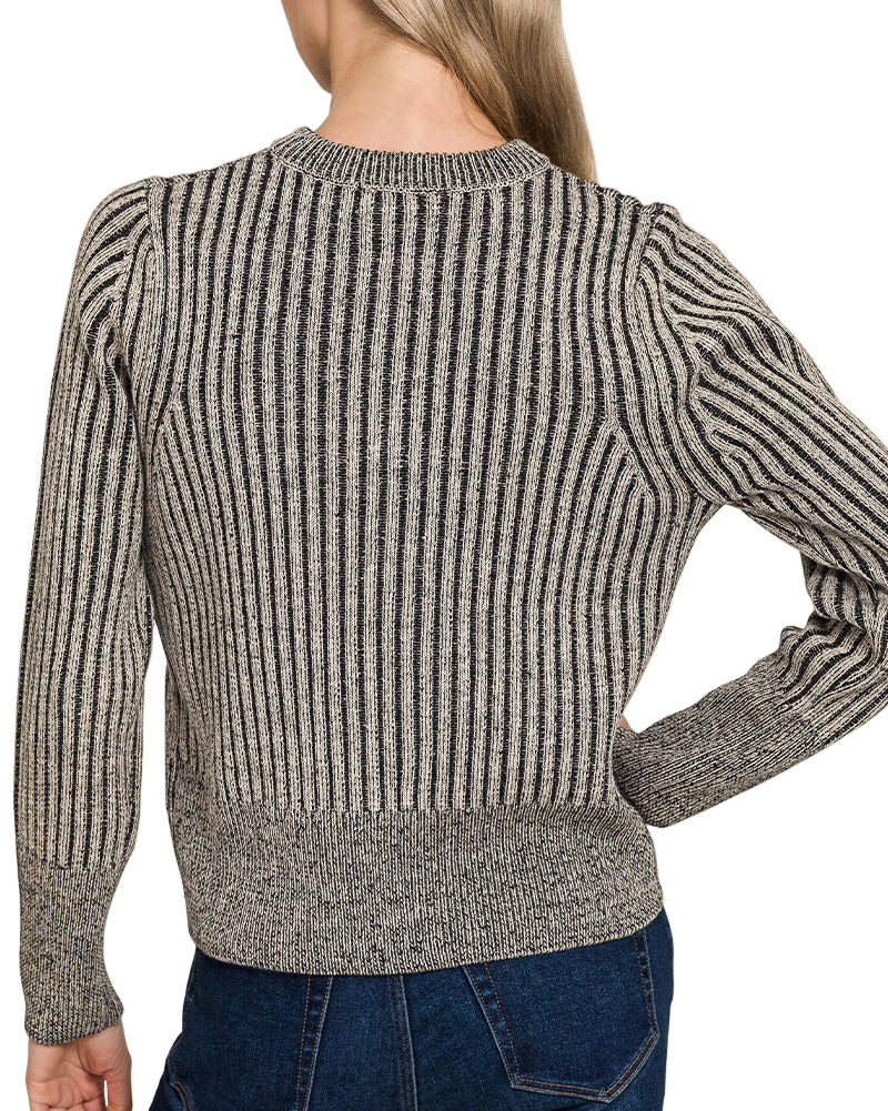 Woman wearing a charcoal ribbed zip up sweater and blue jeans on a white background.