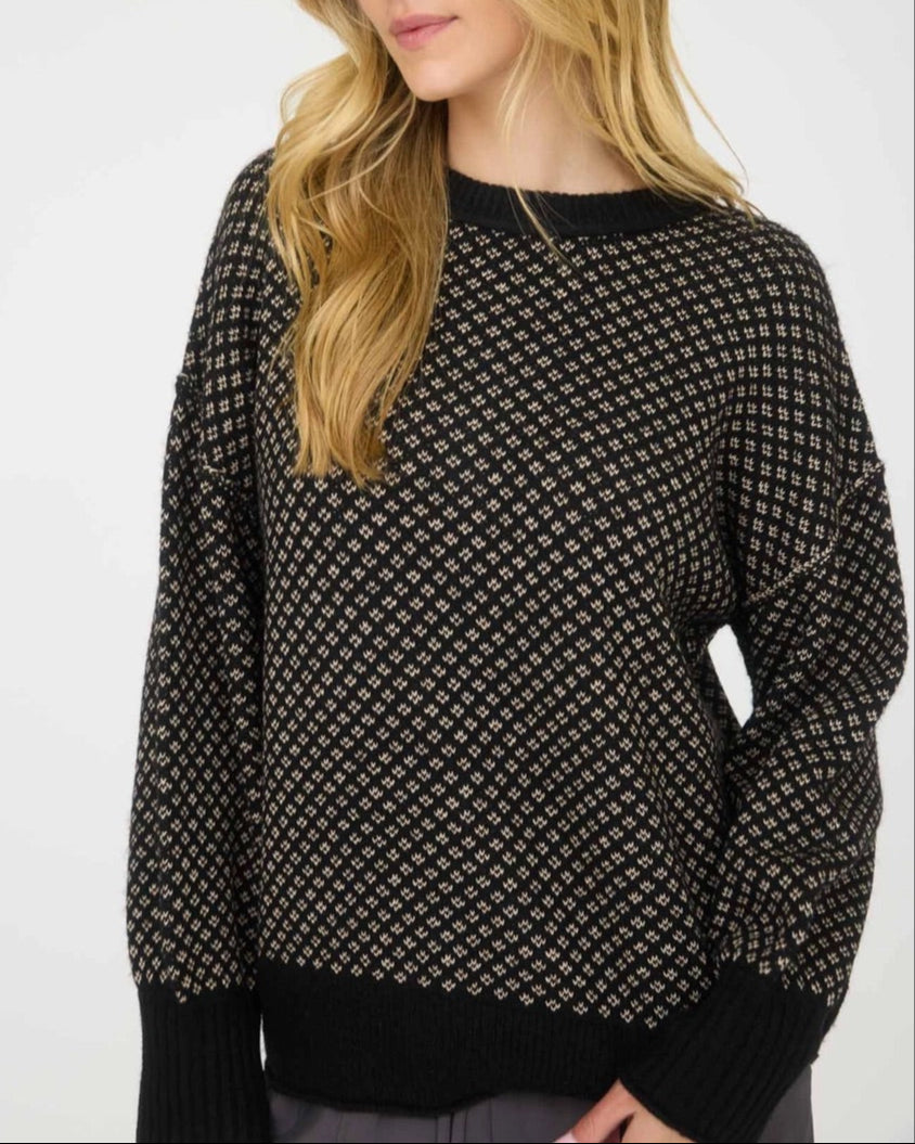 Woman wearing a black patterned sweater against a white background.